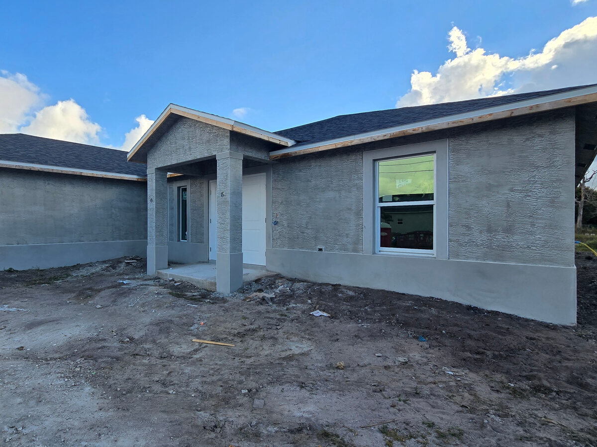 Stucco applied to exterior walls before painting — front view with entry porch