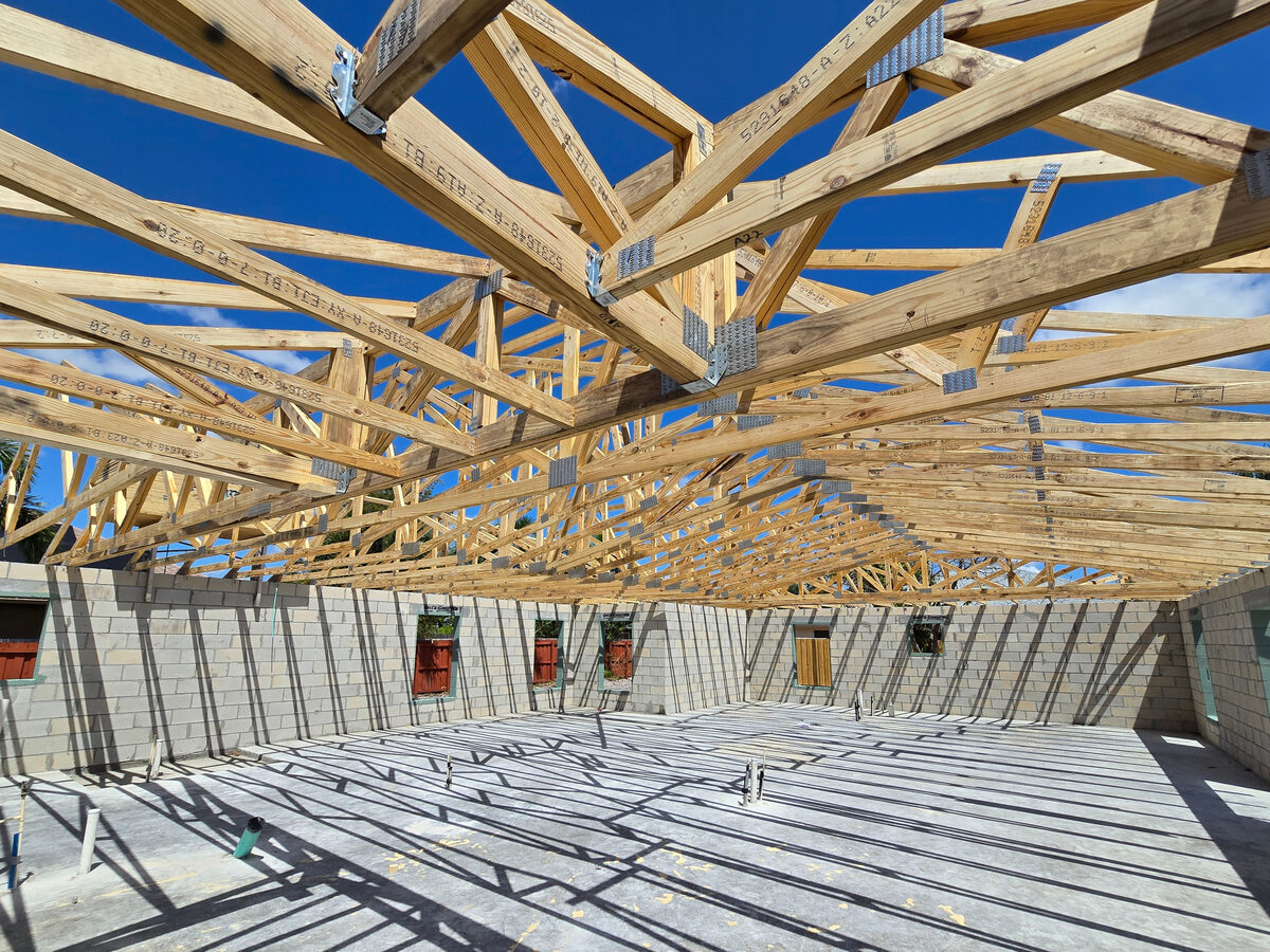 Crane setting engineered wood trusses on block walls