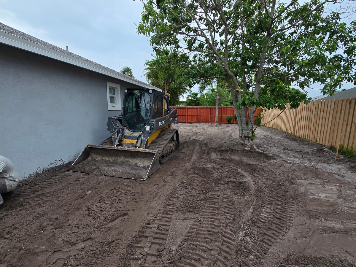 Skid steer grading the yard before sod installation