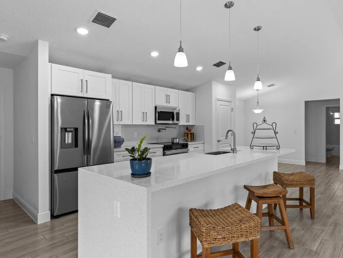 Delivered kitchen with white shaker cabinets, quartz island, and stainless appliances