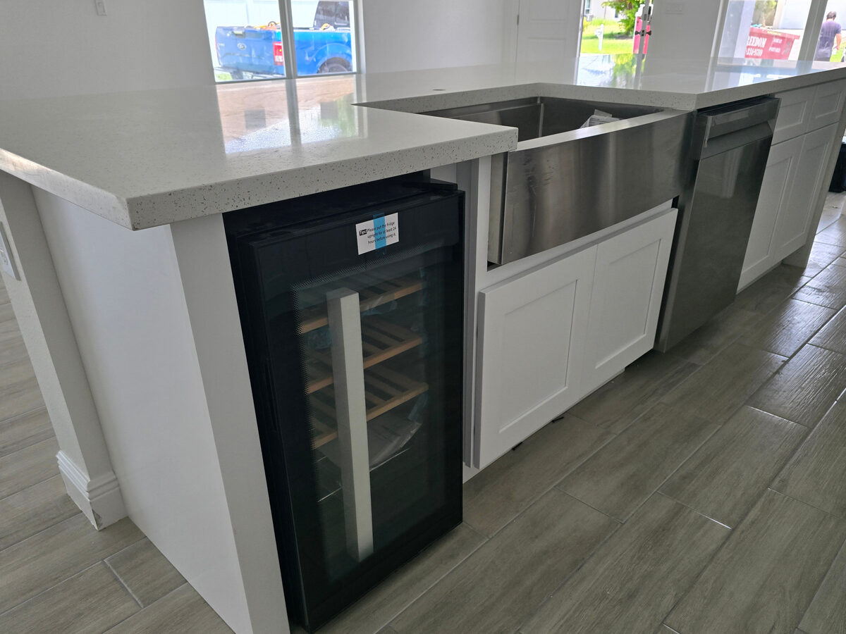 Kitchen island with built-in wine cooler, farmhouse sink, and quartz countertop