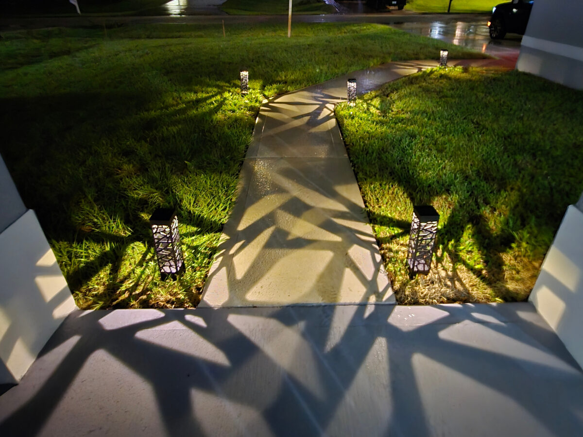 Front walkway at night with decorative solar pathway lights and fresh sod