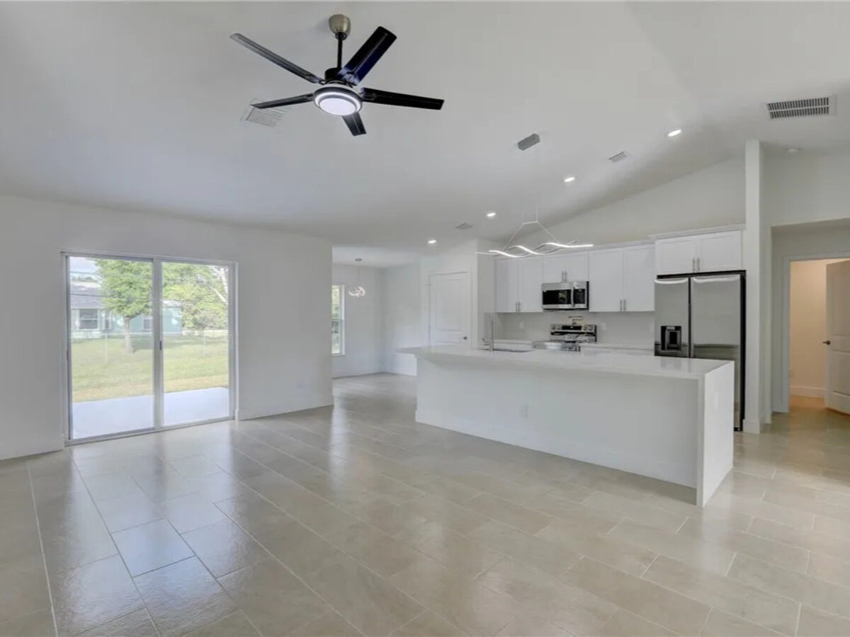 Open living space connected to modern kitchen with pendant lighting