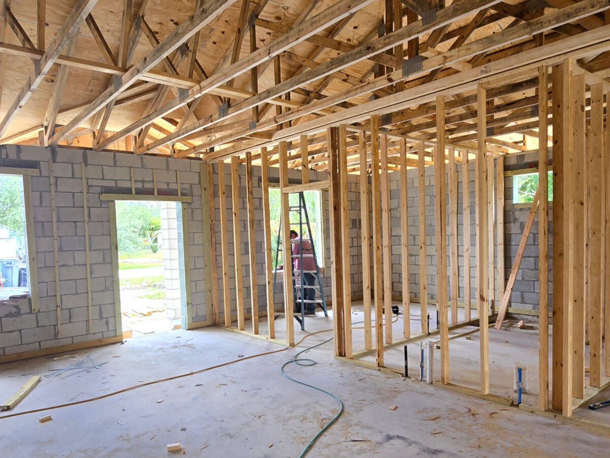 Interior view showing wood framing and roof trusses with worker on site