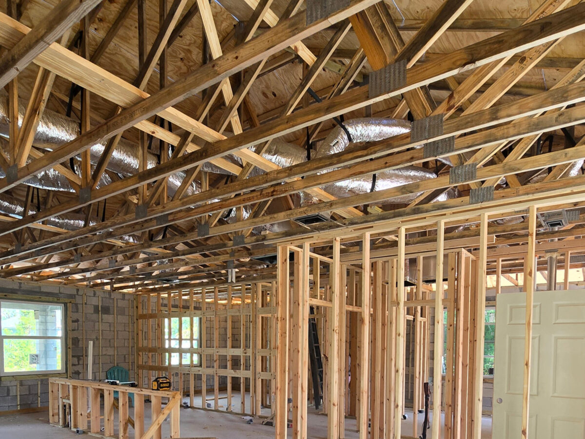 HVAC flex ducts installed through trusses with framing and insulation visible