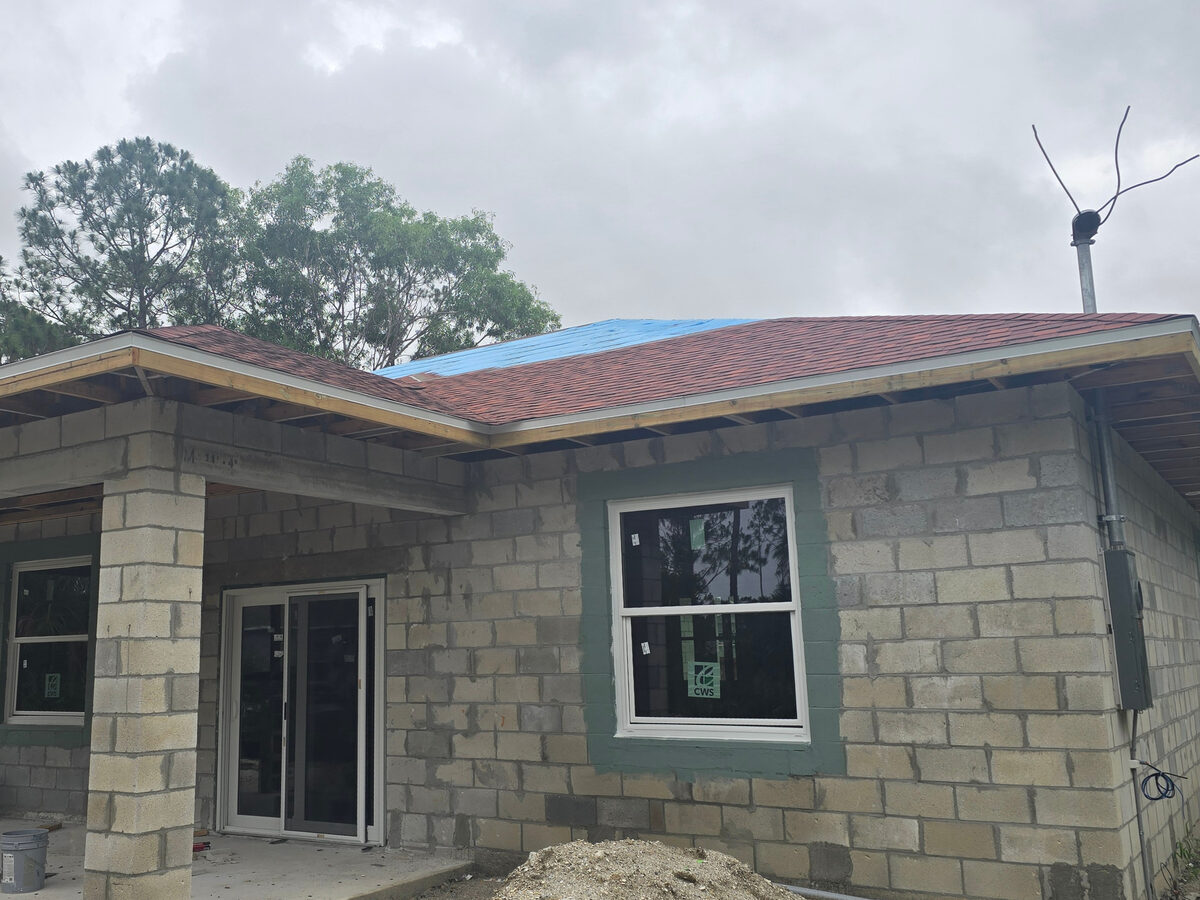 Shingles being installed — front exterior with entry porch and block walls