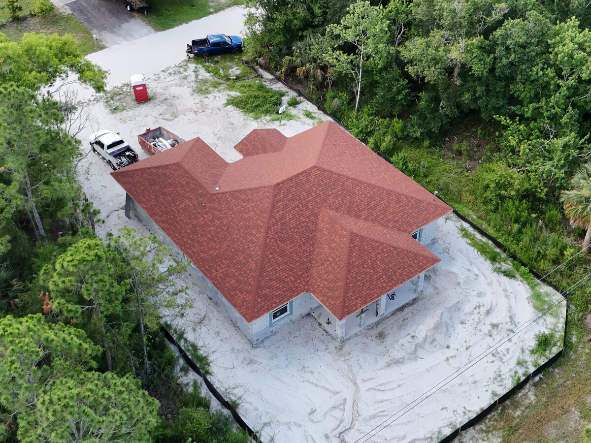 Aerial rear view of fully shingled roof surrounded by trees