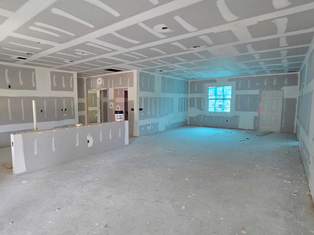 Drywall mudded and taped throughout open-concept living area with recessed light cutouts