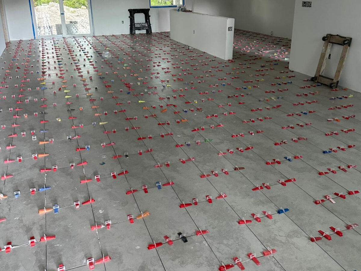 Large-format floor tiles being installed with precision leveling clips throughout living area