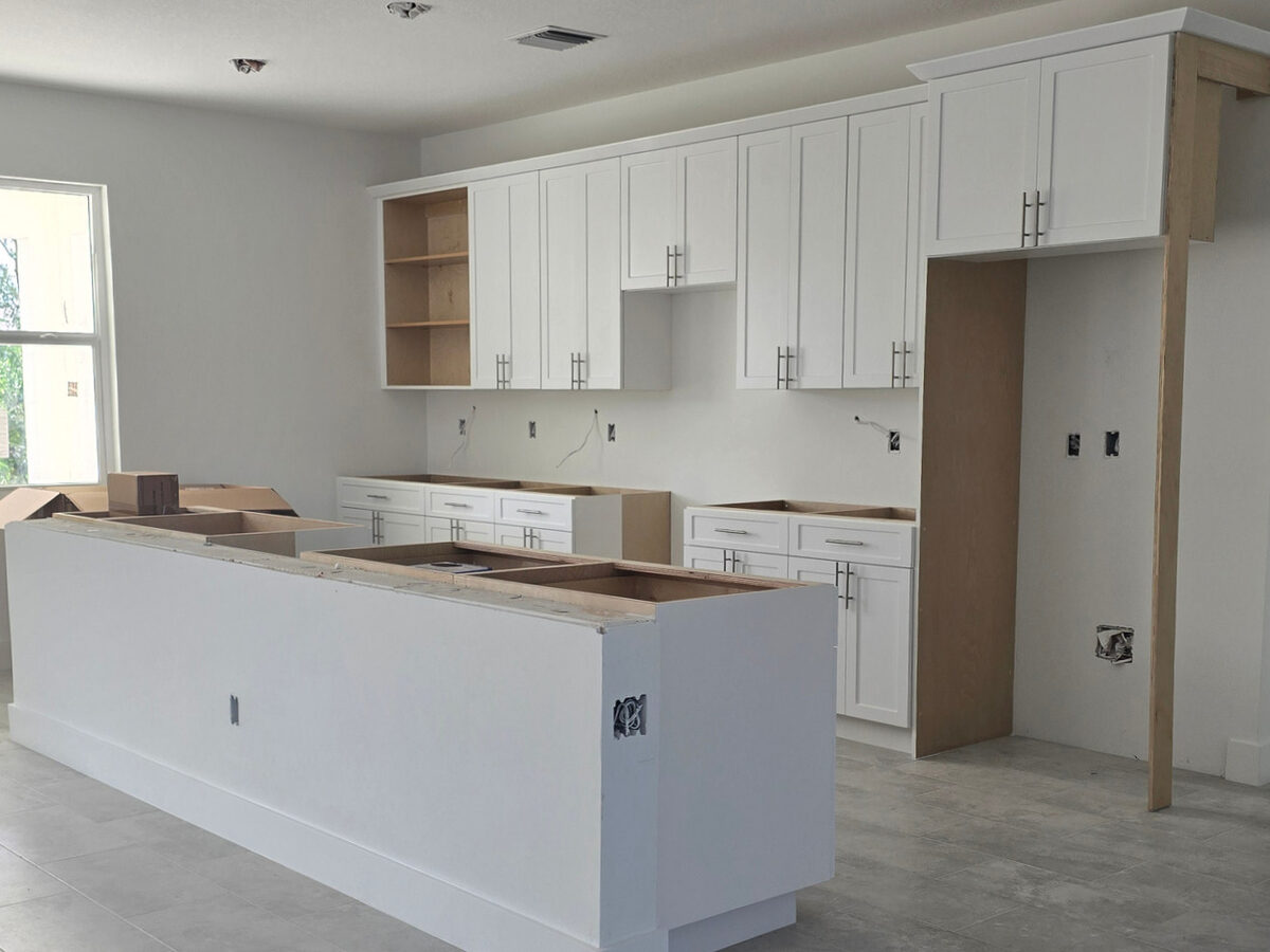 White shaker kitchen cabinets installed with island — awaiting countertop
