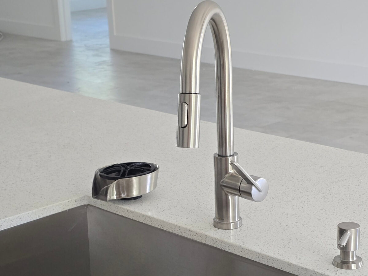 Brushed nickel pull-down faucet and glass rinser on quartz countertop with undermount sink