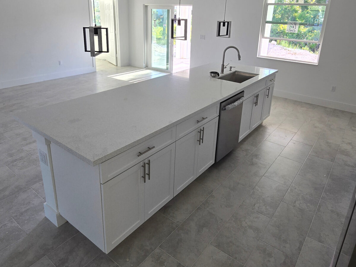 Kitchen island with quartz countertop, pendant lights, dishwasher and sink installed