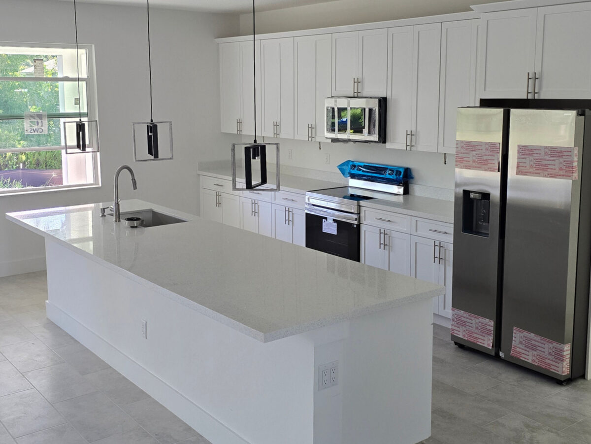 Complete kitchen with stainless steel appliances, quartz island, pendant lighting and tile floor