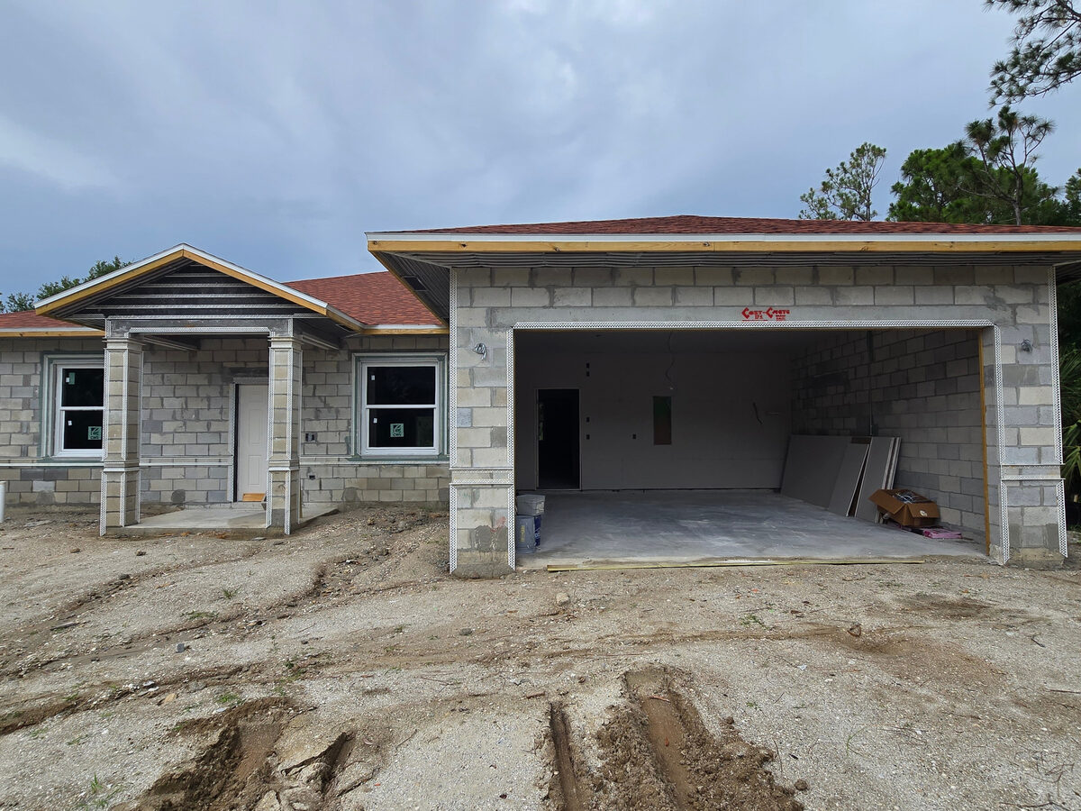Exterior before stucco — block walls with wire lath corners and garage opening