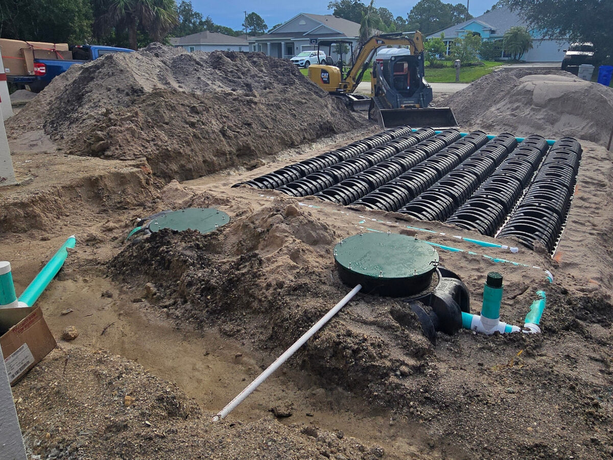 Septic tank and drain field chambers installed with excavator on site