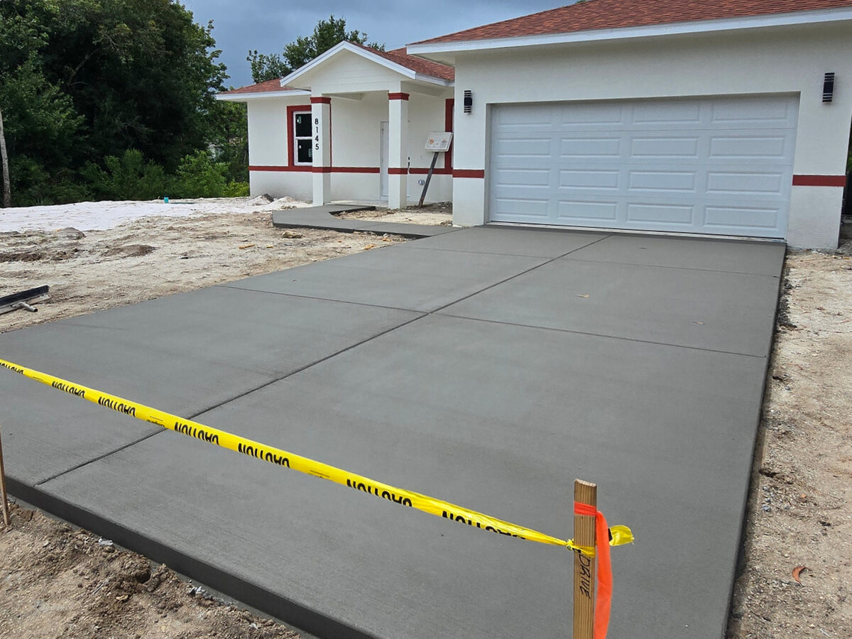 Finished concrete driveway with garage door installed and caution tape
