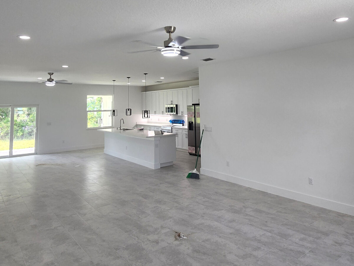 Finished open-concept living area with ceiling fans, kitchen island, recessed lighting and sliding glass doors