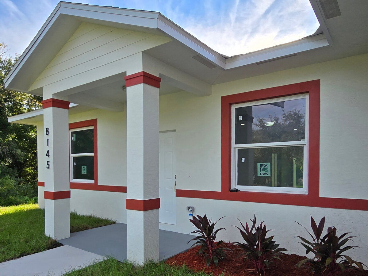 Entry porch at dusk — red accent trim, address numbers 8145, landscaping plants and mulch