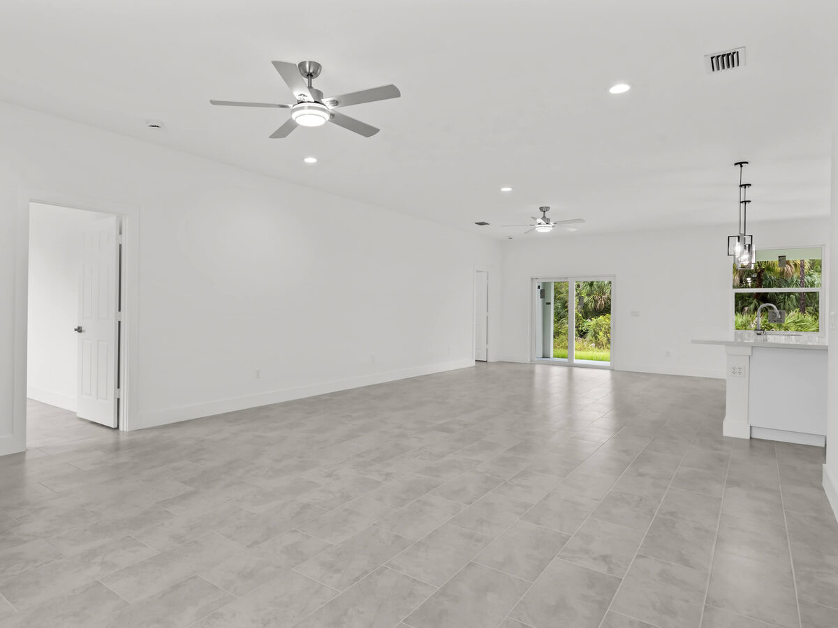 Spacious open living area with ceiling fans, tile flooring and sliding glass doors to backyard